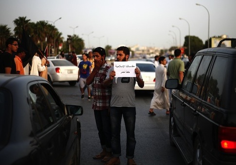 A Libyan follower of Ansar al-Sharia Brigades carries a sign during a protest in front of the Tibesti Hotel, in Benghazi / AP
