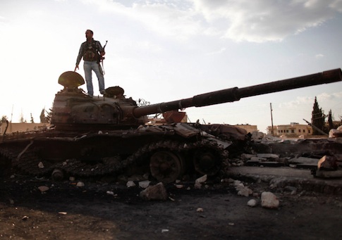 A Free Syrian army fighter stands on a damaged military tank / AP