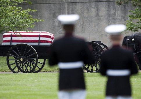 A Marine Corps honor guard watches as a caisson carrying casket