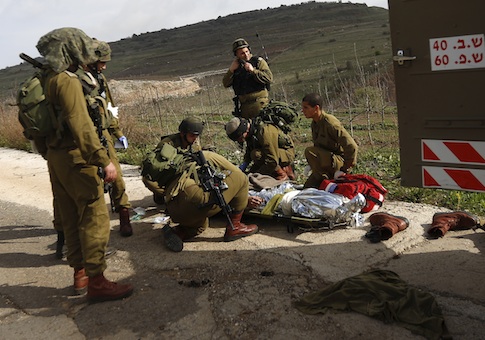 A wounded Israeli soldier is treated in the Golan Heights, Tuesday, March 18, 2014
