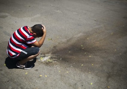 Israeli boy looks at shrapnel at parking lot in the Israeli southern city of Sderot after a rocket fired by Palestinian from Gaza Strip landed in town