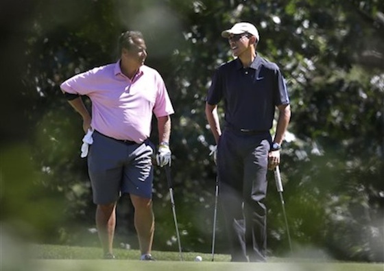 President Barack Obama speaks with golf partner Robert Wolf in Martha's Vineyard /AP