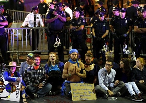 Protesters sit at the intersection of Wall St. and Broad St. in New York, Monday, Sept. 22, 2014