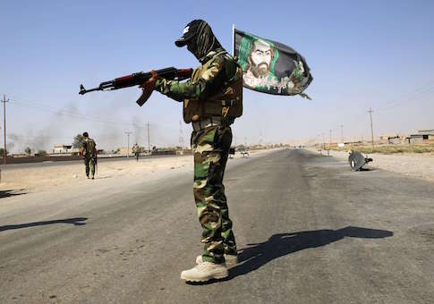 A fighter from the Shi'ite Badr Brigade militia wears a religious flag as he guards a checkpoint recently taken from militants of the Islamic State outside the town of Amerli