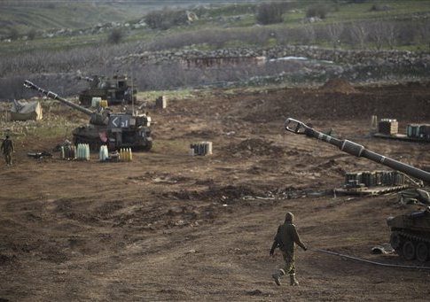 Israeli soldiers walk next to mobile artillery units in the Israeli-controlled Golan Heights near the border with Syria, Wednesday, Jan. 28, 2015