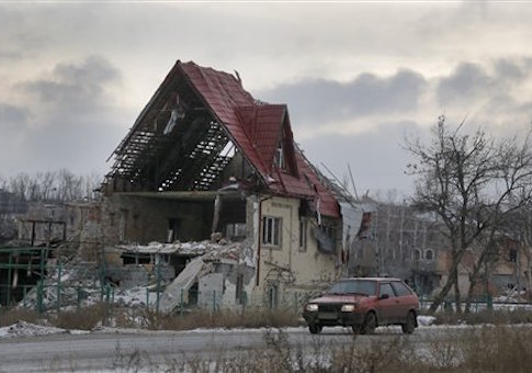 A car drives by a private house destroyed in a recent battles between the Ukrainian army and pro-Russian separatists in Semenivka, Donetsk region, eastern Ukraine