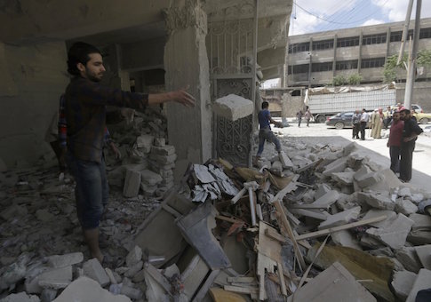 People remove rubble from a site hit by what activists said was a barrel bomb dropped by forces loyal to Syria's President Bashar al-Assad at al-Saleheen neighborhood of Aleppo