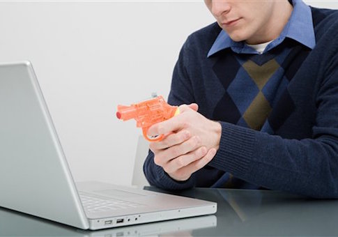 A man pointing a toy gun at a laptop