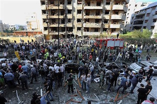 In this file photo taken Tuesday, Nov. 19, 2013, Lebanese people gather at the scene of an attack claimed by the Abdullah Azzam Brigades 