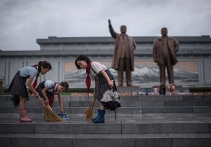 Students clean the steps in front of the statues of late North Korean leaders Kim Il-Sung and Kim Jong-Il at Mansu hill as the country marks 'Victory Day' in Pyongyang on July 27