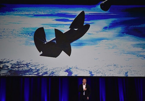 Elon Musk speaks below a computer generated illustration of his new rocket at the 68th International Astronautical Congress 2017