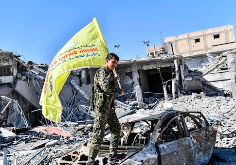 A member of the Syrian Democratic Forces holds up their flag at the iconic Al-Naim square in Raqqa