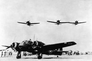 Three US Brewster Buffalo fighters fly over a British Bristol Blenheim bomber at an airfield in Singapore