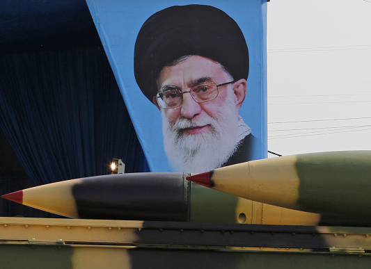 An Iranian military truck carries surface-to-air missiles past a portrait of Iran's Supreme Leader Ayatollah Ali Khamenei